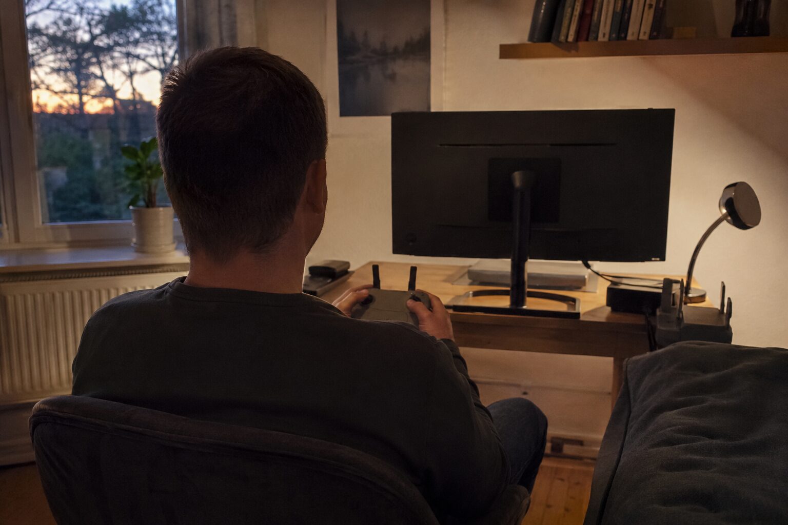 Iemand van achteren in een stoel met een controller in beide handen