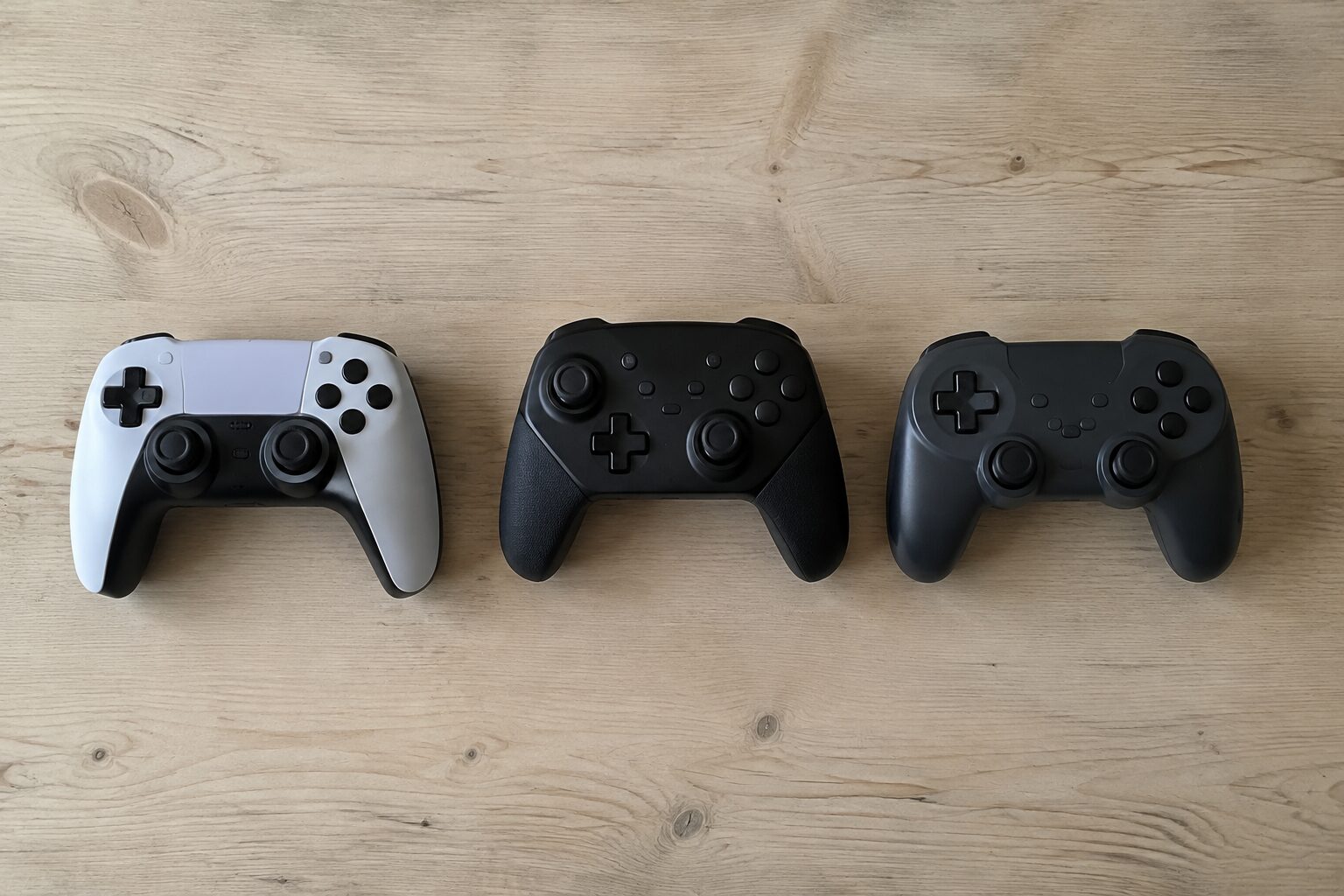 Drie verschillende controllers naast elkaar op een lichte tafel